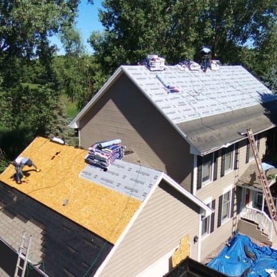 Metal roof installation on residential house during roofing project.